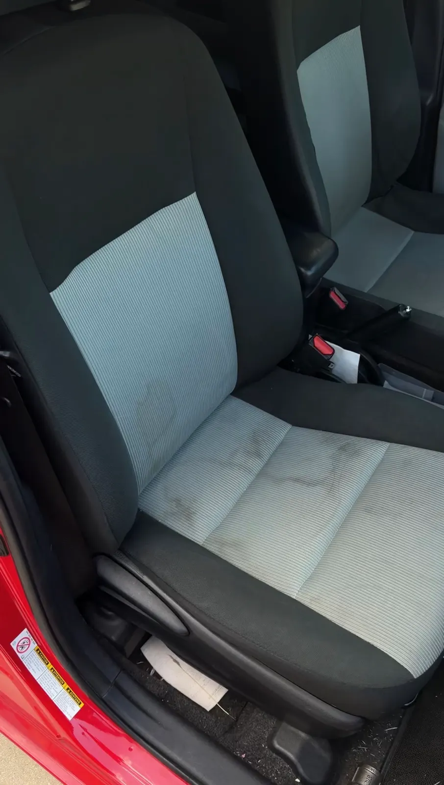 The Prius's passenger seat before work, staining across the cloth cushion and up the backrest.