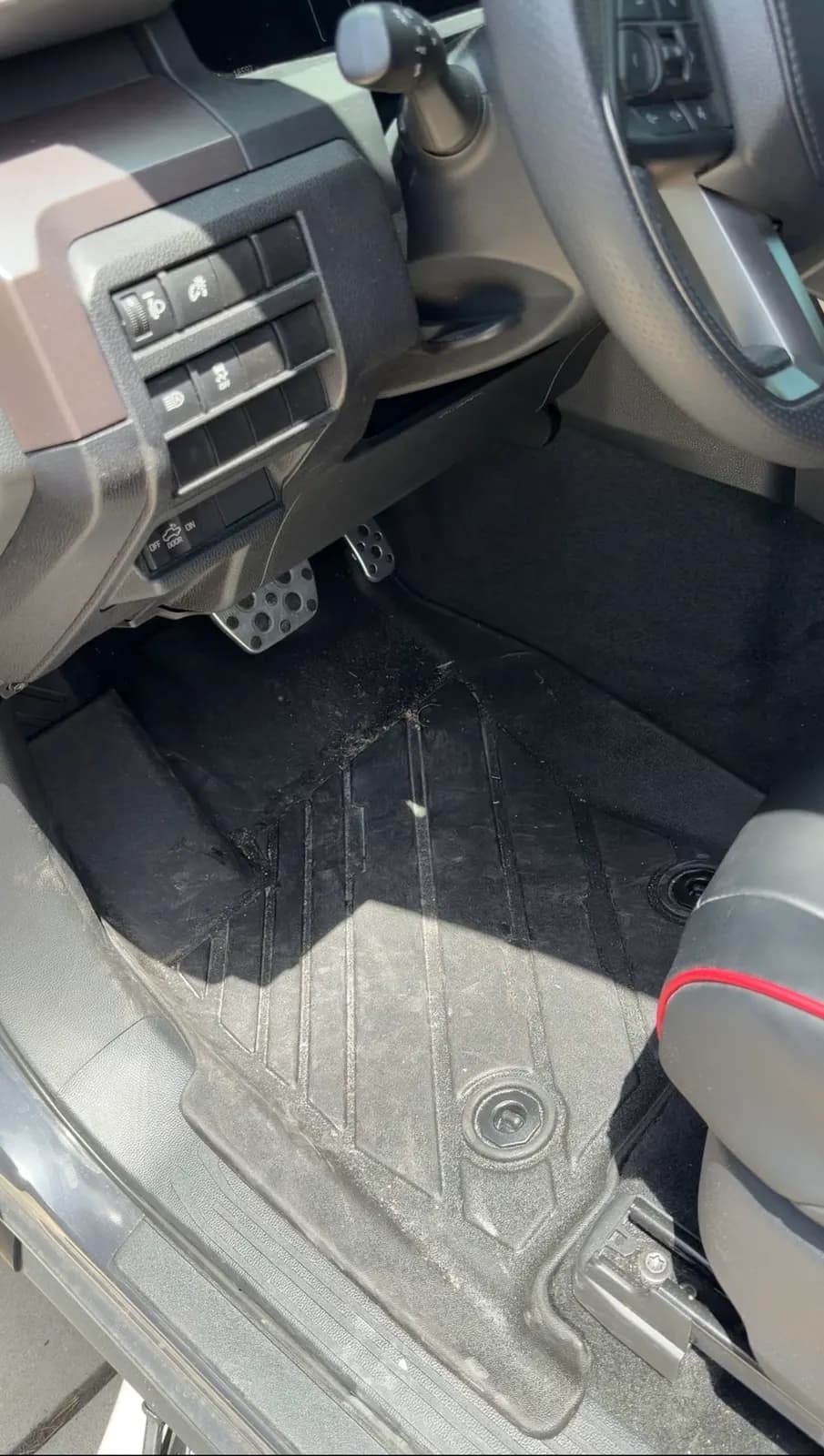 The Tacoma's driver footwell before work, dirt worked into the all-weather mat and the carpet under it.